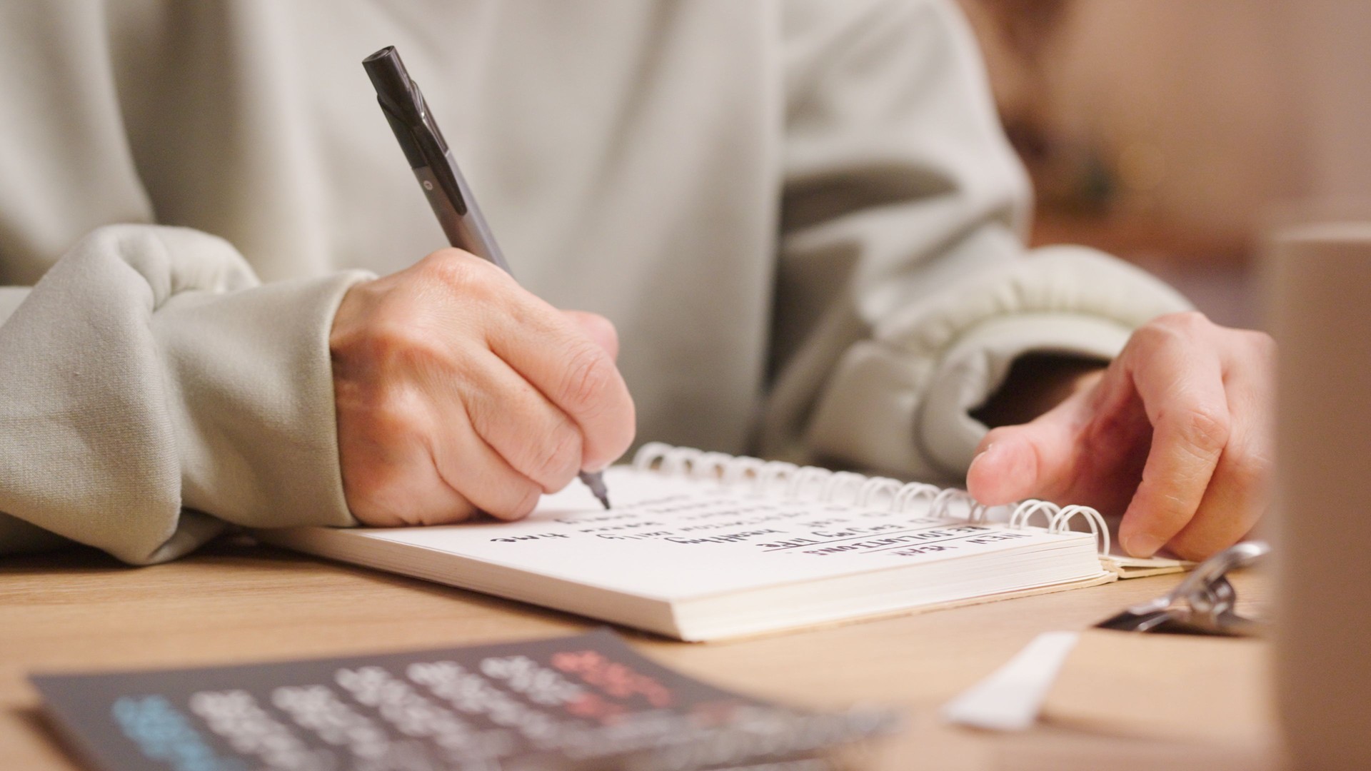 Close up human hand writing New year Resolutions Plans on white paper notebook planning Goal List for well being ,Beginning the new life and enjoy life